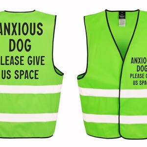 May include: Lime green dog vest with black trim and white reflective stripes. The vest has the text "ANXIOUS DOG PLEASE GIVE US SPACE" printed in black. The vest is designed to alert others to a dog's anxiety.