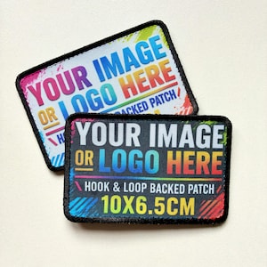 May include: Two rectangular hook and loop patches with black borders. One patch has a white background, the other a black background. Both feature the text "YOUR IMAGE OR LOGO HERE" and "HOOK & LOOP BACKED PATCH 10X6.5CM" in colourful gradient lettering.