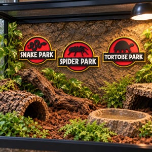 May include: Three circular wall signs with red and yellow borders mounted on a textured brown background. The signs feature black silhouettes of a snake, a spider, and a tortoise, with the text Snake Park, Spider Park, and Tortoise Park.