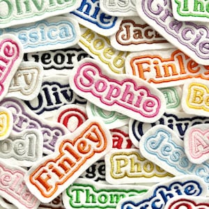 May include: A selection of embroidered name patches in various colours. Names such as "Sophie", "Finley", and "Olivia" are visible, each with a contrasting border. The patches are on a white background, creating a colourful and personalised assortment.