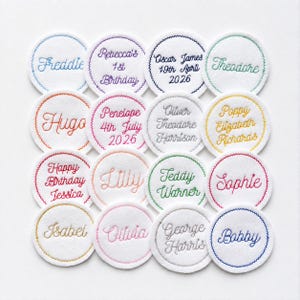 May include: A collection of sixteen circular white felt patches arranged in a grid. Each patch features colourful embroidered text, including names like Freddie, Rebecca, Hugo, Penelope, Oliver, Poppy, Jessica, Lilly, Teddy, Sophie, Isabel, Olivia, George, and Bobby.
