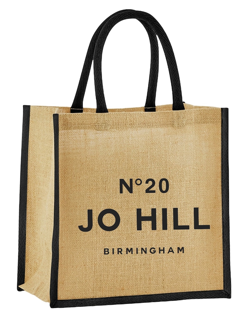May include: A brown jute tote bag with black handles and trim. The bag has the text "No. 20 JO HILL BIRMINGHAM" printed on the front.