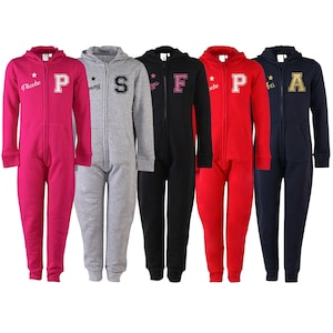 May include: Five hooded onesie pyjamas in fuchsia, grey, black, red, and navy. Each has a different initial and name on the chest, with a star. The pyjamas have a full-length zip.