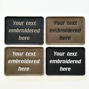 May include: Four rectangular patches with embroidered text. The patches are in black and brown, with the text "Your text embroidered here" in contrasting colors. The patches are likely for customization.