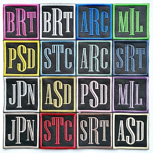 May include: A collection of embroidered patches with various three-letter initials in different colors. Each patch has a black background and a white border. The initials are in a bold, stylized font, with colors like pink, blue, and green.