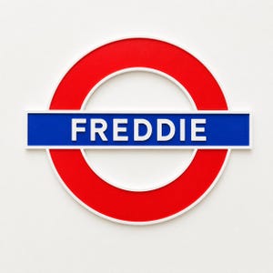 May include: A circular sign featuring a red ring with a white border and a horizontal blue bar across the center. The word FREDDIE is printed in white capital letters on the blue bar, mimicking the style of a London Underground station sign.