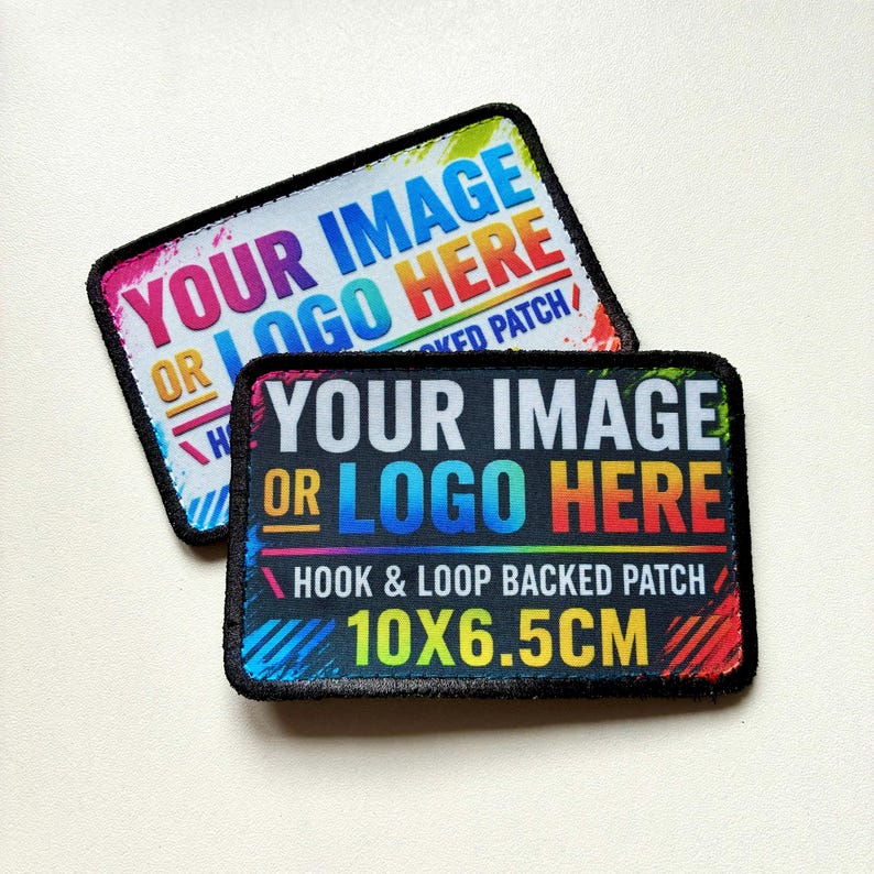 K&ouml;nnte beinhalten: Zwei rechteckige Klett-Aufn&auml;her mit schwarzem, gen&auml;htem Rand. Ein Aufn&auml;her hat einen wei&szlig;en Hintergrund, der andere einen schwarzen. Beide zeigen den Text YOUR IMAGE OR LOGO HERE und HOOK & LOOP BACKED PATCH 10X6.5CM.