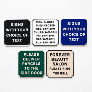 May include: Five square signs with rounded corners and raised lettering. Colours include black, white, blue, green, and cream. Text includes business hours, delivery instructions, and custom messaging options like SIGNS WITH YOUR CHOICE OF TEXT.