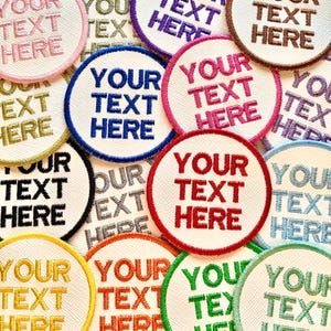 May include: A selection of embroidered patches, each featuring the text "YOUR TEXT HERE". The patches are circular with a white base and colourful borders, such as blue, red, pink, and green.