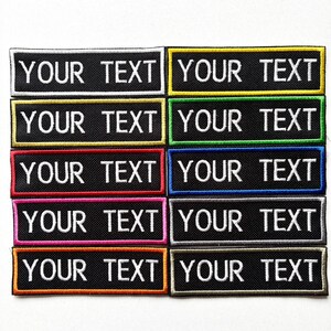 May include: A selection of black rectangular patches, each embroidered with the words "YOUR TEXT" in white. The patches have borders in various colours, such as white, yellow, green, red, blue, pink, and orange.