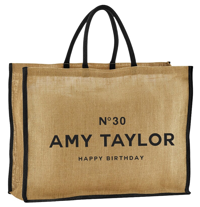 May include: A brown burlap tote bag with black handles and trim. The bag has the text "N&deg;30 AMY TAYLOR HAPPY BIRTHDAY" printed on the front.