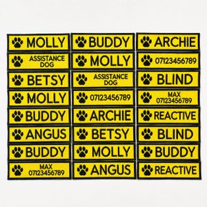 May include: A collection of yellow rectangular patches with black text and paw print icons. The patches display names like "Molly", "Buddy", and "Archie", along with phrases such as "Assistance Dog" and phone numbers.