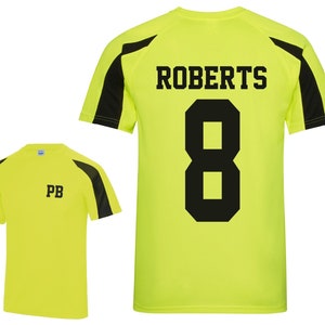 May include: A neon yellow athletic shirt with black accents on the shoulders and sleeves. The back of the shirt displays the name "ROBERTS" above the number "8" in black. The front of the shirt has the initials "PB" in black.