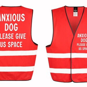 May include: Red dog vest with white reflective stripes and black trim. The vest has the text "ANXIOUS DOG PLEASE GIVE US SPACE" in white. The vest is designed to alert others to a dog's anxiety.