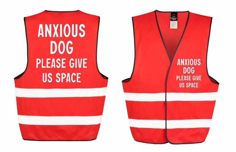 May include: Red dog vest with white reflective stripes and black trim. The vest has the text "ANXIOUS DOG PLEASE GIVE US SPACE" in white. The vest is designed to alert others to a dog's anxiety.