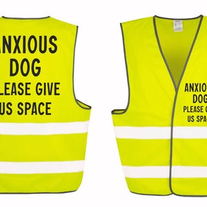 May include: Two neon yellow dog vests with reflective white stripes. The vests have black text that reads "ANXIOUS DOG PLEASE GIVE US SPACE". One vest is shown from the front and the other from the back.