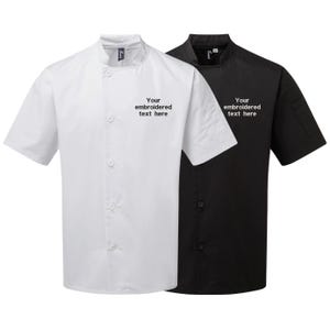 May include: Two short-sleeved chef's jackets are shown, one white and one black. Each jacket features a mandarin collar, button-up front, and a small pocket on the left sleeve. The text "Your embroidered text here" is printed on the left chest of each jacket.