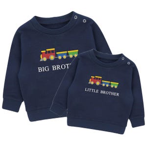 May include: Two navy blue sweatshirts with a train graphic. One says "BIG BROT" and the other says "LITTLE BROTHER" in white text. The train is red, yellow, blue, and green. Each sweatshirt has two buttons on the shoulder.