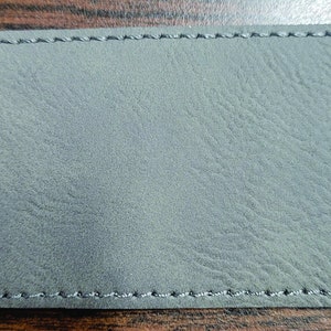 May include: A gray leather patch with a stitched border.