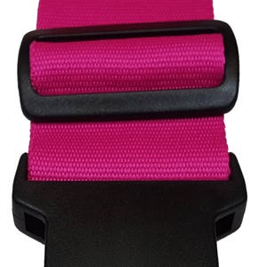 The image features a pink -coloured strap with a black plastic buckle, typically used for securing items like luggage.
