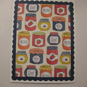 May include: A greeting card with a pattern of illustrated jam jars in various colors. The jars are labeled with text such as "Mixed Berry," "Orange Marmalade," and "Blueberry Jam." The card has a dark blue scalloped border.