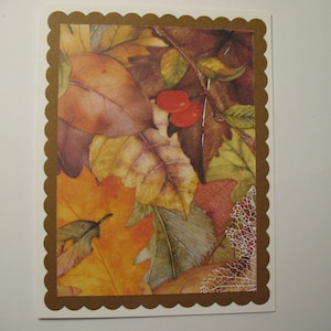 May include: A card with a brown scalloped border and a colorful autumn leaf design. The leaves are in shades of brown, yellow, orange, and green. There are also a few red berries on a branch.
