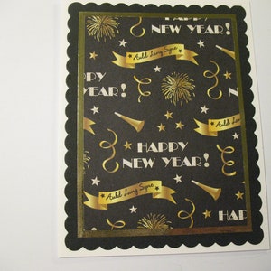 May include: A black and gold card with a scalloped border. The card has a repeating pattern of gold stars, fireworks, and confetti. The text "Happy New Year!" is written in gold lettering. The text "Auld Lang Syne" is written in gold lettering on a gold banner.