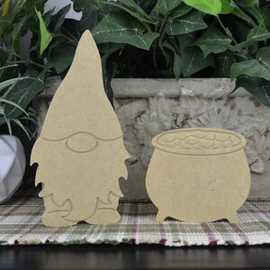 May include: Unpainted wooden gnome and pot of gold cutout. The gnome is wearing a tall hat and has a beard. The pot of gold is filled with coins.