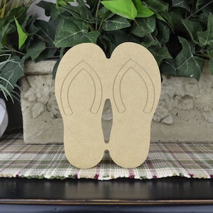May include: A pair of unfinished wooden flip-flop cutouts. The flip-flops are brown and have a simple design.