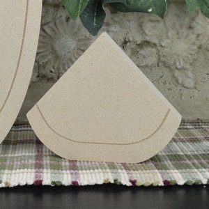 May include: A beige unfinished wooden cutout of a half circle shape. The cutout has a rounded edge and a slightly raised edge around the perimeter.