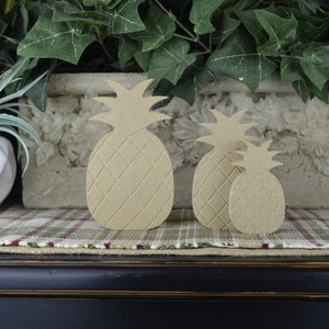 Puede incluir: Tres formas de pi&ntilde;a de madera de diferentes tama&ntilde;os, con una superficie texturizada, est&aacute;n dispuestas sobre una superficie de tela a cuadros. Las pi&ntilde;as son de color marr&oacute;n claro y est&aacute;n hechas de madera.