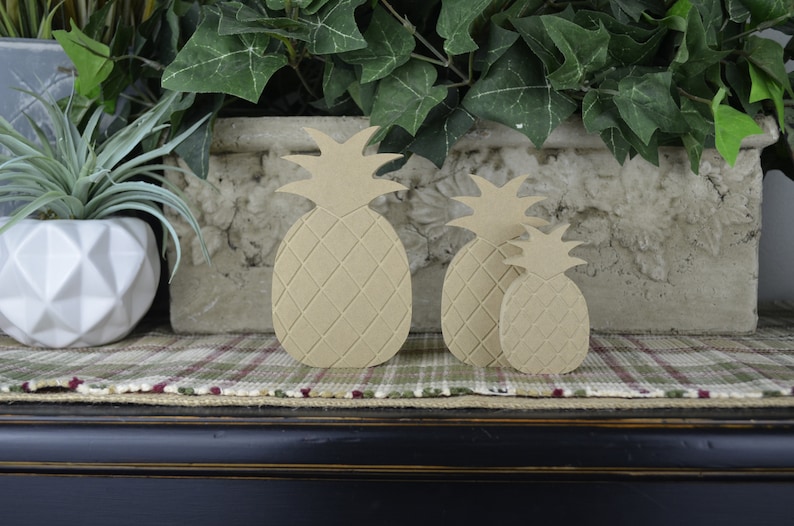 Puede incluir: Tres formas de pi&ntilde;a de madera de diferentes tama&ntilde;os, con una superficie texturizada, est&aacute;n dispuestas sobre una superficie de tela a cuadros. Las pi&ntilde;as son de color marr&oacute;n claro y est&aacute;n hechas de madera.