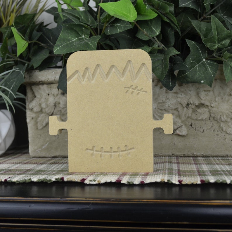 Puede incluir: Corte de madera sin pintar de un monstruo de Frankenstein con detalles cosidos. El corte est&aacute; hecho de madera sin terminar y est&aacute; listo para ser pintado o decorado.