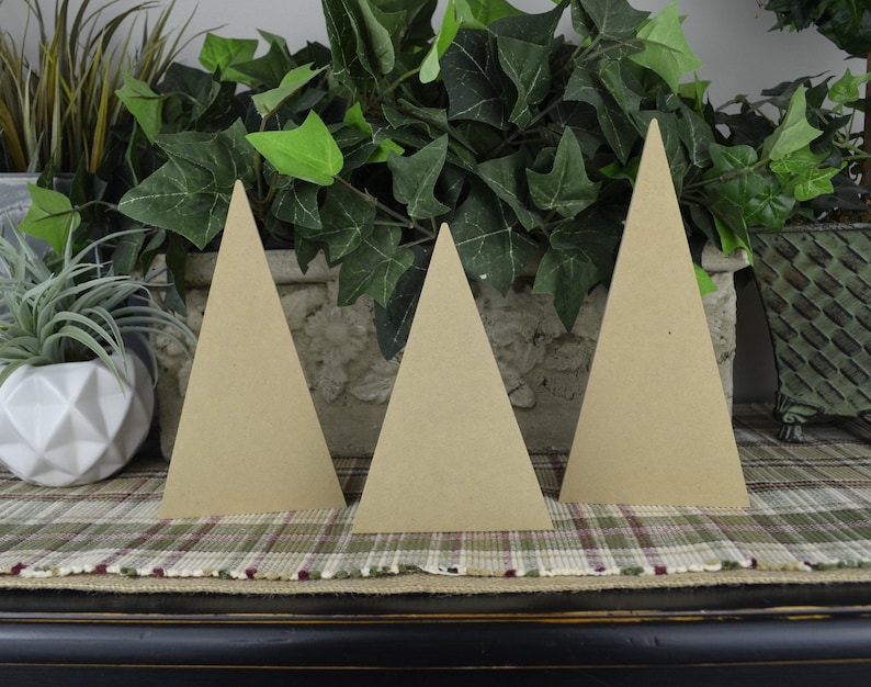 K&ouml;nnte beinhalten: Drei unfertige Holz-Dreiecksformen, die an Weihnachtsb&auml;ume erinnern, sind auf einer karierten Oberfl&auml;che angeordnet. Die B&auml;ume sind aus Naturholz gefertigt und haben einen rustikalen Look.