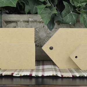 May include: Four unfinished wooden tags of various sizes and shapes. Two are rectangular and two are shaped like a teardrop. All have a hole in the top for hanging.