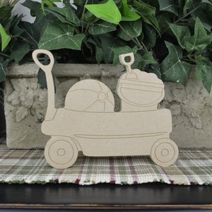 May include: Wooden cutout of a red wagon with a beach ball, pail, and shovel. The wagon is on a plaid surface.