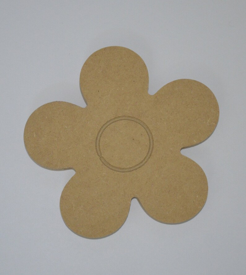 May include: A wooden flower-shaped cutout with a circle in the center. The flower has six petals and is a light brown color.