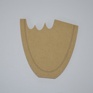 May include: A brown wooden cutout in the shape of a vase with a scalloped top edge. The cutout has a double line around the edge.