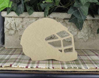May include: A wooden cutout of a hockey goalie mask. The mask is brown and has a wire cage design.
