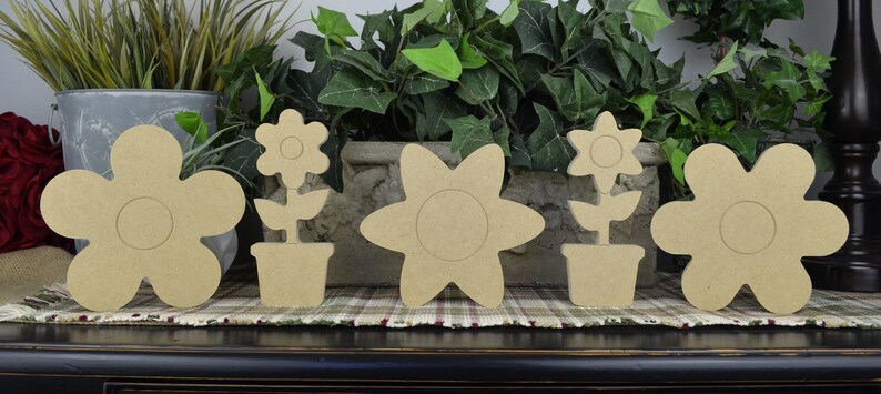 May include: Five unfinished wooden flower shapes, two with stems and pots, ready for painting and decorating.  These wooden flower shapes are perfect for crafting and home decor.