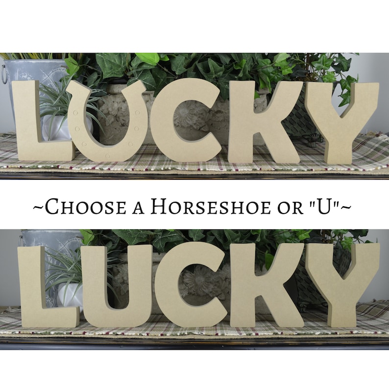 May include: Two sets of wooden letters spelling "LUCKY" with a horseshoe or a "U" in the center. The letters are painted a light brown color and are arranged on a plaid surface.