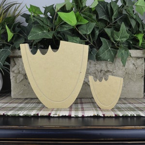 May include: Two unfinished wooden cutout shapes of a heart, one large and one small. The shapes are made of light brown wood and have a smooth surface.