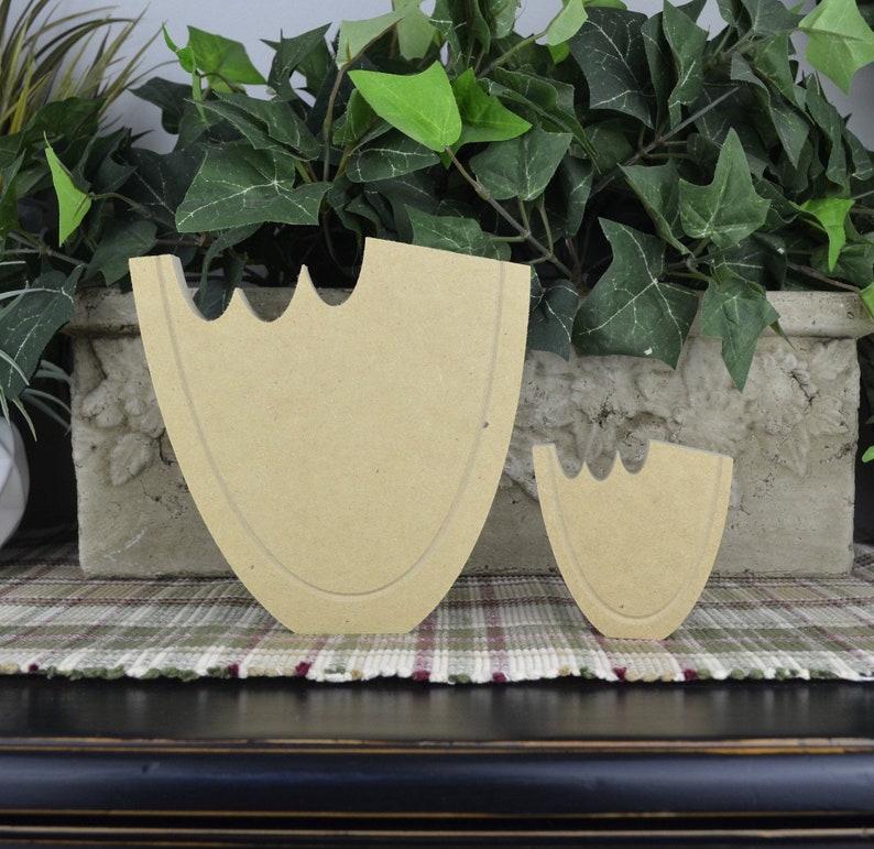 May include: Two unfinished wooden cutout shapes of a heart, one large and one small. The shapes are made of light brown wood and have a smooth surface.