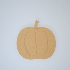 May include: A brown wooden pumpkin cutout, perfect for crafting and decorating. The pumpkin has a simple design with a stem and lines for the pumpkin's ridges.