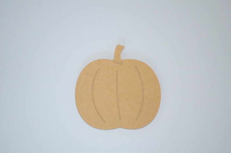May include: A brown wooden pumpkin cutout, perfect for crafting and decorating. The pumpkin has a simple design with a stem and lines for the pumpkin's ridges.