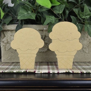 May include: Two wooden ice cream cone shapes, one with a single scoop and the other with two scoops. The cones are textured to look like waffle cones.