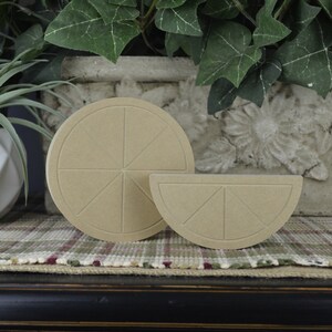 May include: Two unfinished wooden craft shapes of a whole lemon and a lemon slice. The shapes are made of a light brown wood and have a textured surface.