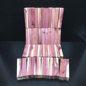 May include: A collection of wooden dowels in various shades of pink and brown. The dowels are arranged in a staggered pattern, creating a visual texture.