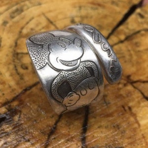 May include: A silver ring with a Mickey Mouse design and the word "MOUSE" engraved on the side.