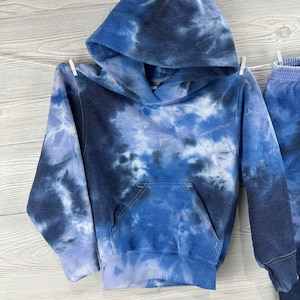 May include: Blue tie-dye hoodie with a hood and a front pocket.